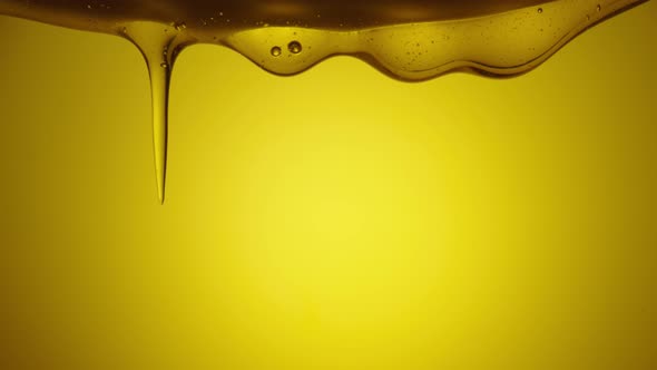 A Stream of Golden Thick Honey Spills on a Yellow Background alt