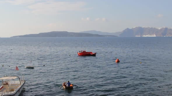 A man is paddling in the aegean sea, inside the Santorini caldera. alt