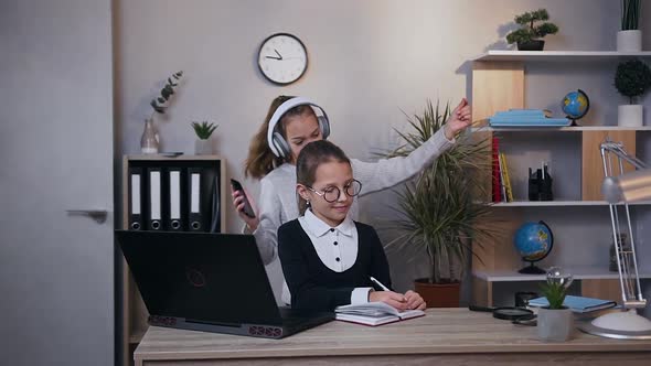 Girl in Earphones which Dancing Under Inflammatory Music while Another Smiling Girl alt