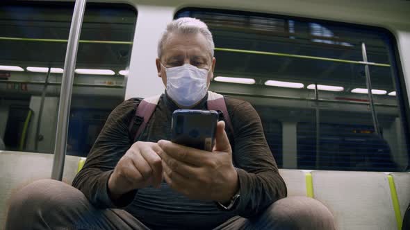 An Old Man in a Protective Mask Rides the Subway alt