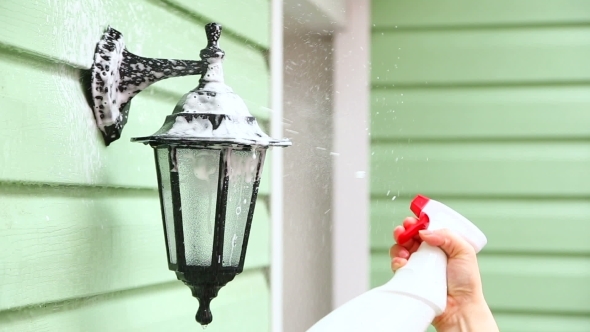 Human Hand Spraying Detergent Onto Street Lamp