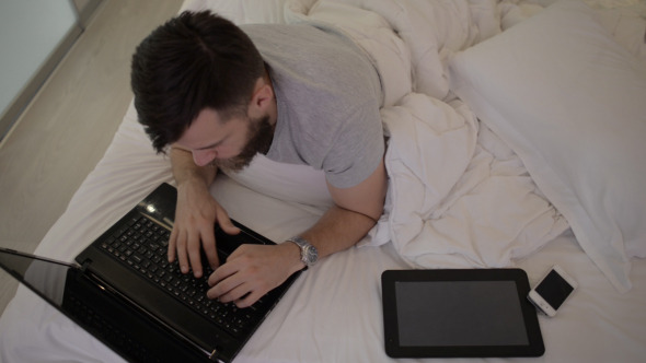 Beard Man Using Keyboard of Laptop in Bed Beard Man Using Keyboard of Laptop in Bed