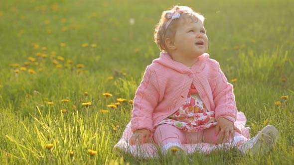 Portrait Of A Baby Sitting On The Green Grass Portrait Of A Baby Sitting On The Green Grass