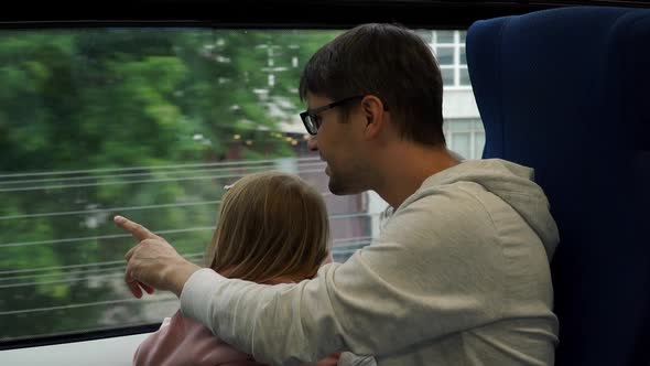 Father with Little Girl Look at Big City Out of Train Window While Traveling By Railway