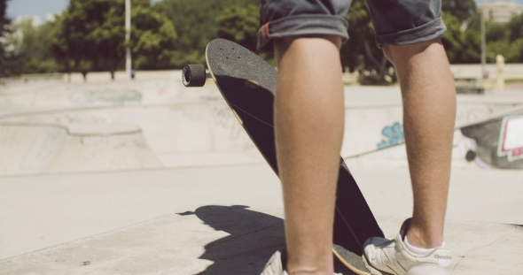 Man Standing At a Skate Park With His Longboard Man Standing At a Skate Park With His Longboard