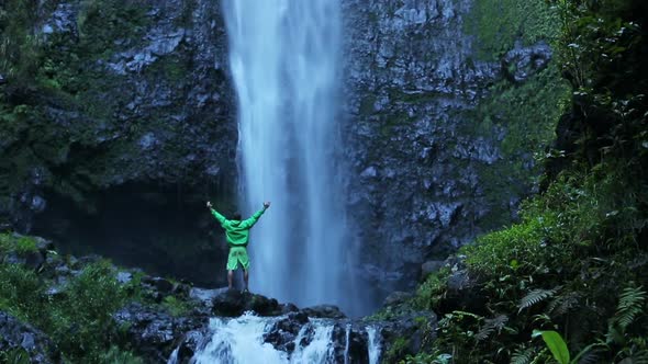 Man Standing At Base Of Massive Waterfall