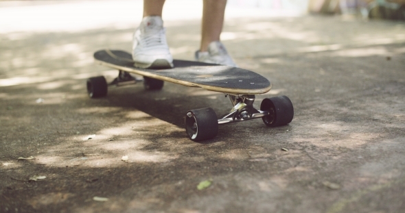 Feet Of Man Skating On Longboard At The Street alt