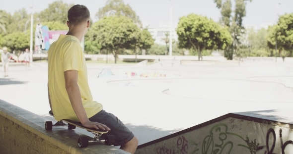 Man Sitting On a Skateboard Balanced On a Wall Man Sitting On a Skateboard Balanced On a Wall