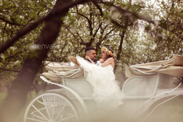 Bride and groom sitting in a white carriage