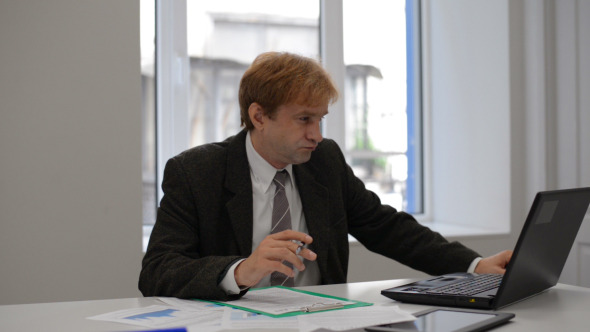 Businessman Reading Documents on Laptop Businessman Reading Documents on Laptop