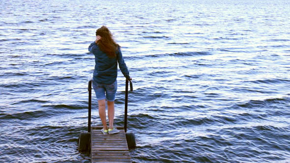 Girl Sitting on a Pier Looking at the Ocean Girl Sitting on a Pier Looking at the Ocean