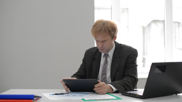 Anxious Businessman Using Tablet at Work Anxious Businessman Using Tablet at Work