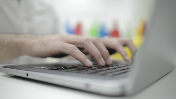 Fingers Typing on Keyboard of Laptop in Office