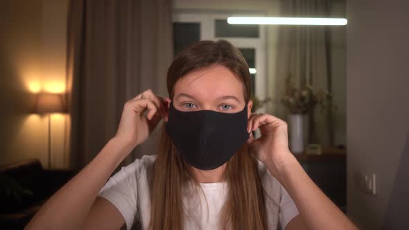 Woman at Home Wears a Black Fabric Protective Mask That She Sewed on a Sewing Machine