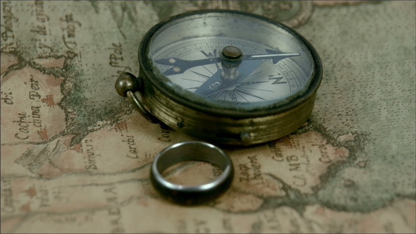 A Compass and a Ring on Top of the Map