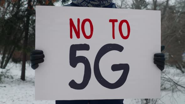 A person is standing in the park and protesting with a banner No To 5G. Picket alt