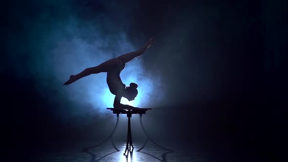 Acrobat Girl Executes Tricks . Smoke Background. Slow Motion. Silhouette alt