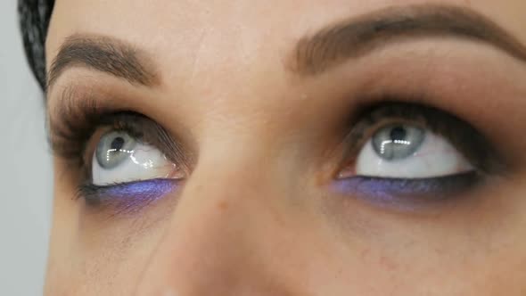 Beautiful Blue Eye to a Young Woman Whom Apply Smoky Eyes with the Help of Special Brush Lilac and alt