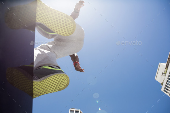 Athletic man about to do a back flip in the city