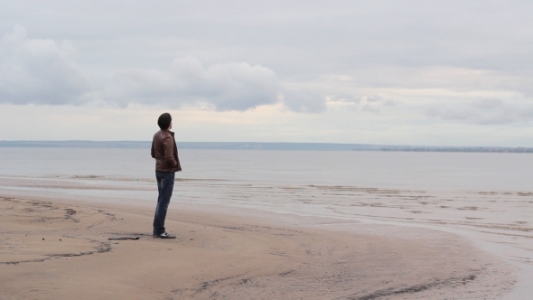 Young Man Crouching By The Sea