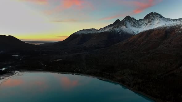 Mountain with a snowy top, forest at the foot, a mirror lake and sunset in Eklutna Lake, Alaska, USA alt