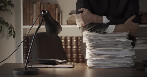 Businessman Leaning Over Stack of Paperwork