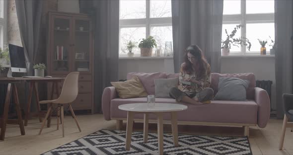 Girl Sits Down To Read A Book On The Sofa