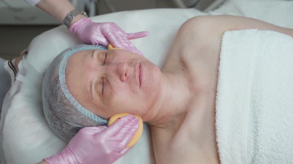Cleansing the Skin of the Face of an Adult Woman in a Beauty Salon alt