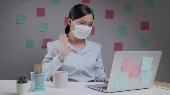 Asian woman wearing mask happy meeting by video call with laptop