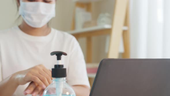 Asian woman using alcohol gel hand sanitizer wash hand before open laptop for protect coronavirus.