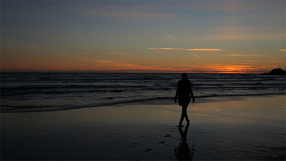 Girl is Walking on the Beach at Sunset