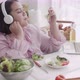 Young asian woman fat eating salad food and wearing headphone for listening music with delicious. - VideoHive Item for Sale
