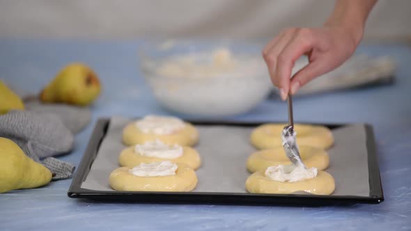 Woman making open buns with cream cheese and pear.	