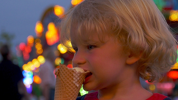 Young Child Eating A Ice Cream On Funfair