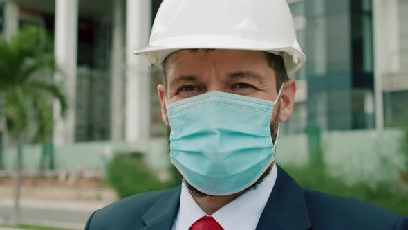 Senior Engineer Face Protective Mask in a Business Suit Wearing a White Safety Helmet with a Beard alt