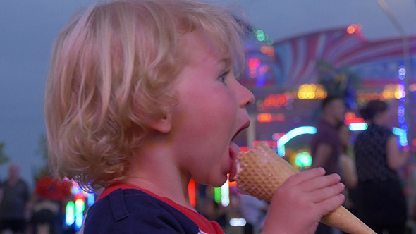 Young Child Eating A Ice Cream At A Funfair