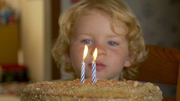 Cute Kid Blowing Out A Birthday Candle