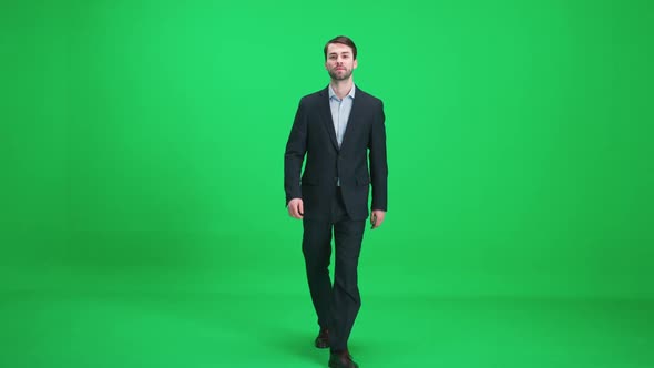 Passerby Men in a Suit Walks on a Green Background a Happy Men Comes Closer and Looks at the Camera alt