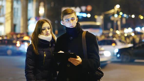 A Young Couple is Looking for a Way in the City Uses Navigation on a Tablet alt