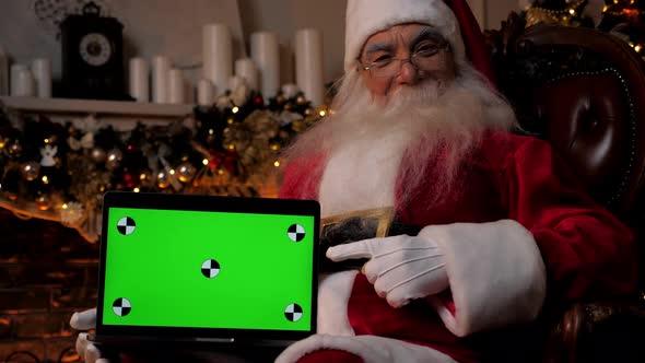 Smiling Santa Claus Points Finger at Laptop Green Screen Christmas Shopping alt