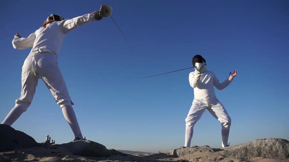 A man and woman fencing on the beach alt