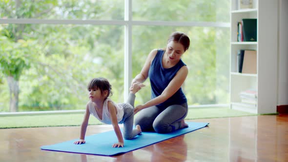 Young mother training her cute daughter for exercise