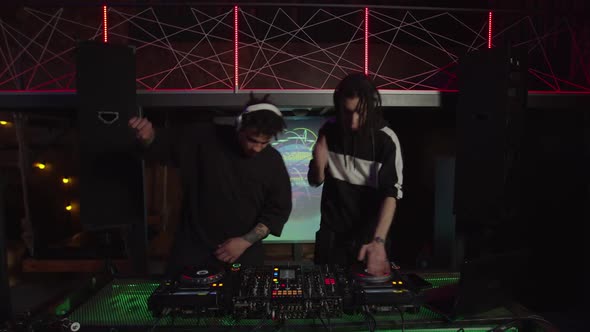 Energetic Trendy Multiracial Male Djs Dancing and Playing Disco House Music on Sound Mixer in Club alt