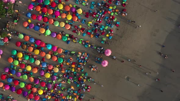 Colorful umbrellas on the sandy beach in Bali. Aerial corkscrew shot above the Double six beach with alt