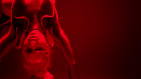 Live Camera Follows Movement of Flexible Woman Bending Backwards Dancing in Split in Red Neon Light alt