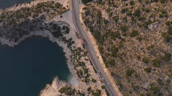 Aerial View of Cars Driving Through Scenic Sea and Mountains on a Summer Day alt