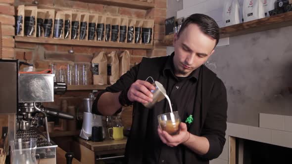 Barista making coffee latte art. Pouring milk into cappuccino.