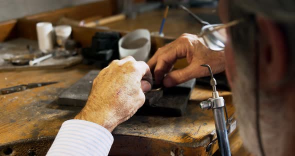 Goldsmith manufacturing jewellery in workshop alt
