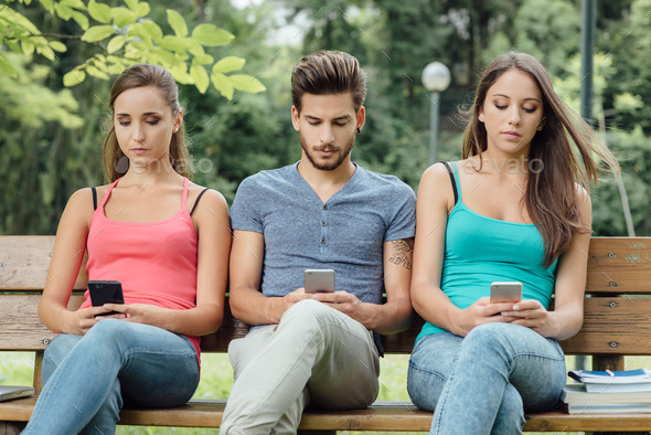 Teens at the park using smart phones - Stock Photo - Images