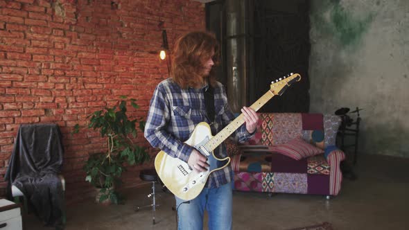 Portrait of Young Man Musician with Long Red Hair Playing Electric Guitar at Home Slow Motion alt